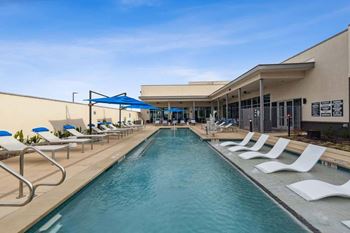A long rectangular pool with white chairs on the side.